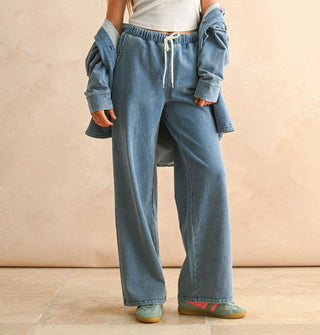 Model wears soft-washed blue drawstring pants with elastic waist and a matching shirt jacket worn slouched down off shoulders