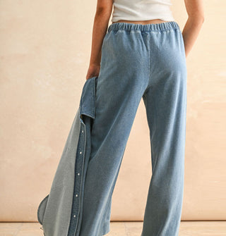 Model wears soft-washed blue pants with elastic waist and holds a matching shirt jacket in one hand
