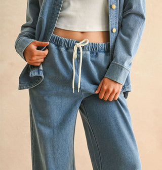 Model wears a matching set of soft-washed blue drawstring elastic waist pants and button-down shirt jacket