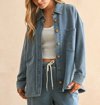 Model wears a soft-washed blue shirt-jacket with gold buttons paired with matching drawstring pants