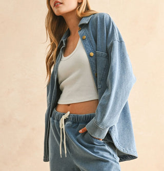 Model poses with hand in the pocket of soft-washed blue drawstring pants paired with a matching button-down shirt-jacket