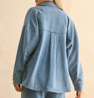 Model turning away from camera wears a soft-washed blue shirt-jacket with back yoke box pleat