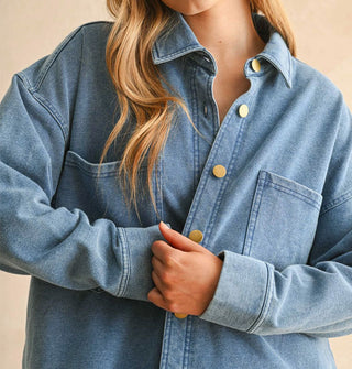 Model closes the opening of a soft-washed blue button-down shirt-jacket