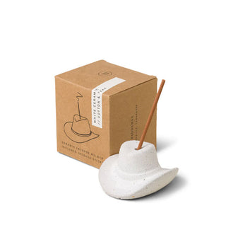 White ceramic cowboy hat incense holder fitted with an incense stick next to its brown gift box packaging