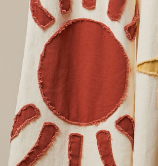 Closeup of a rough-edged orange sun appliqué on white fabric