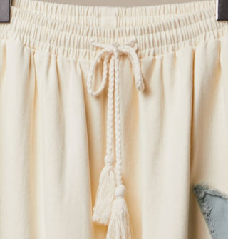 Elastic tie waist on a pair of white  washed cotton pants held by hanger clamps