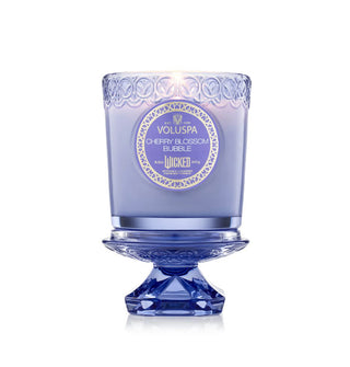 Embossed purple Wicked edition Cherry Blossom Bubble Voluspa candle jar atop its pedestal-shaped lid
