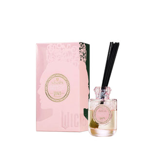 Pink glass Voluspa oil diffuser bottle with black reeds inserted sits next to its matching decorative gift box