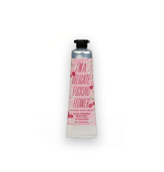 Silver tube of I'm a Delicate Fucking Flower Natural Hand Cream in Wild Cherry Blossom With a Hint of Sandalwood scent features a decorative pink label and black cap