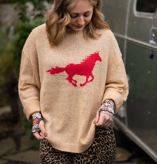 Model wears a tan sweater with red galloping horse design