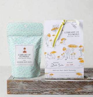 Inner and outer pouches of Library of Flowers Willow & Water Bath Salts feature blue floral patterning and yellow-capped mushroom artwork
