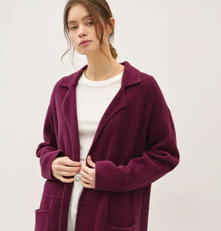 Model wears a long burgundy fuzzy coat/cardigan with notched collar and pockets