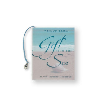 Cover of Wisdom from Gift From the Sea by Anne Morrow Lindbergh features a seaside photograph and an attached blue ribbon with charm is shown at left