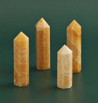 Grouping of four marbleized yellow jade point towers on a green backdrop