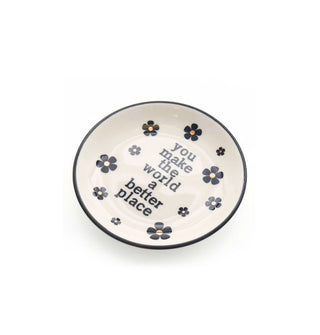 Small round white dish with black and gold flower accents and a black rim says, "YOu make the world a better place" in black lettering